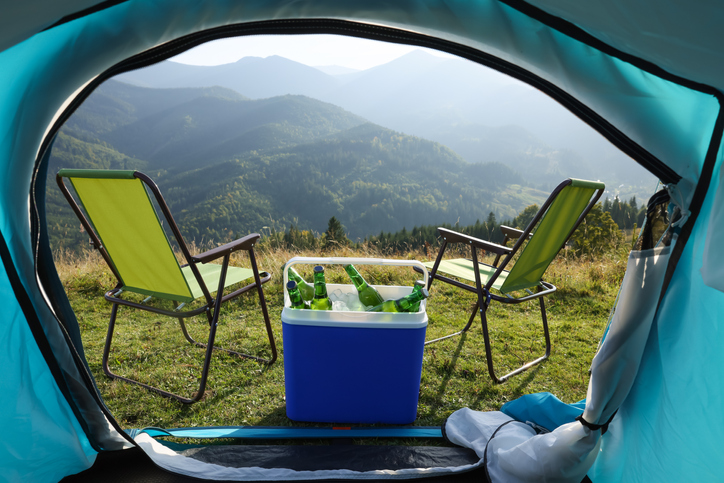 Chairs and cool box with bottles of beer in mountains, view from tent