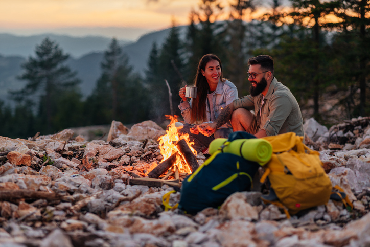 Young couple sitting at the top of the mountain over a fire
