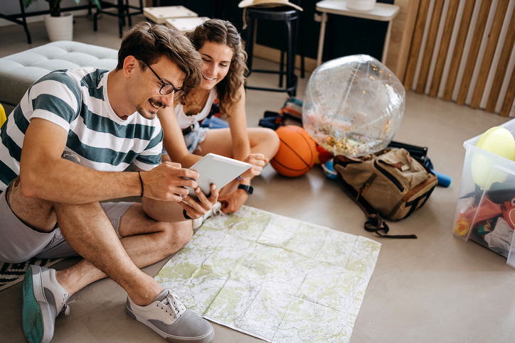 Couple planning vacation trip with a map and a tablet