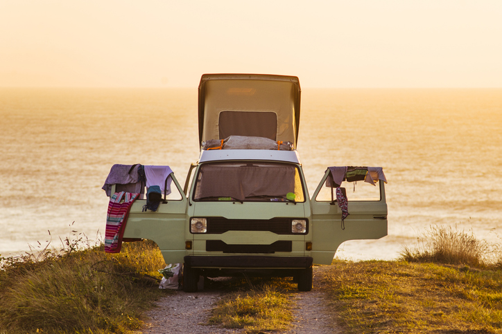 A surfers' old van parked on the seaside at sunset.