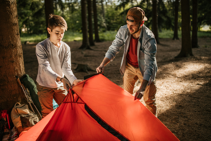 Father and son assembling tent in forest