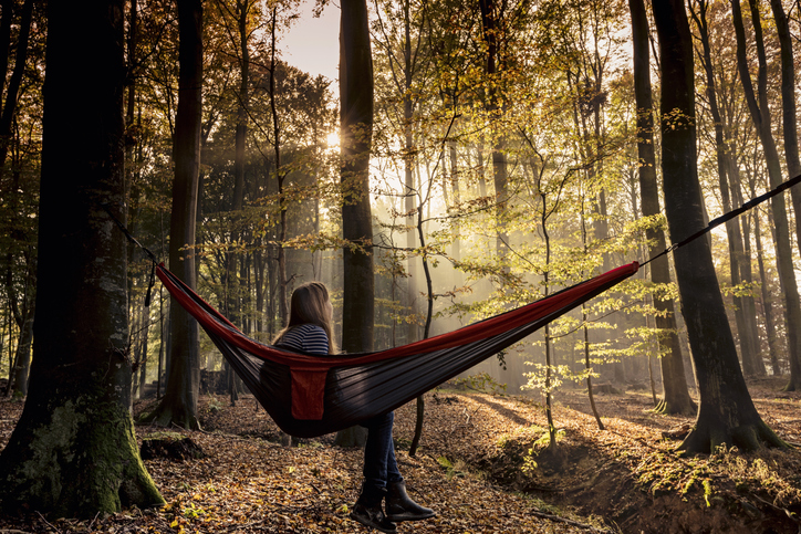 girl, 13, relaxing in a hammock that is tied up in the forest