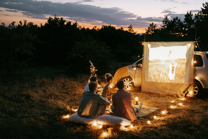 Group of friends enjoying movie night outdoors in nature