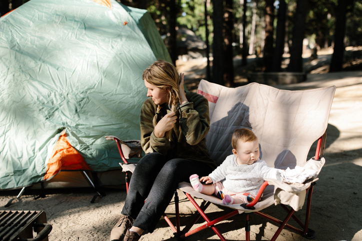 A mother and her baby girl sitting on a camp chair outdoors while camping