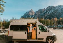 Young Caucasian woman looking from camper van on the background of Dolomites in autumn