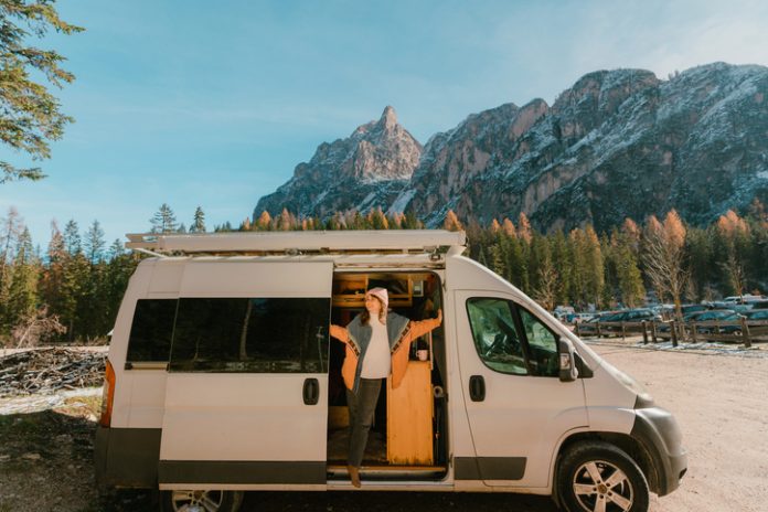 Young Caucasian woman looking from camper van on the background of Dolomites in autumn
