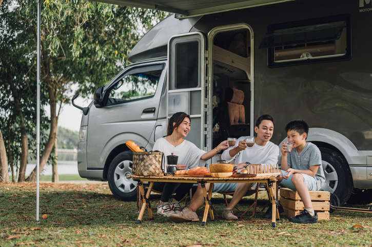family talking at picnic table by the camper trailer in nature