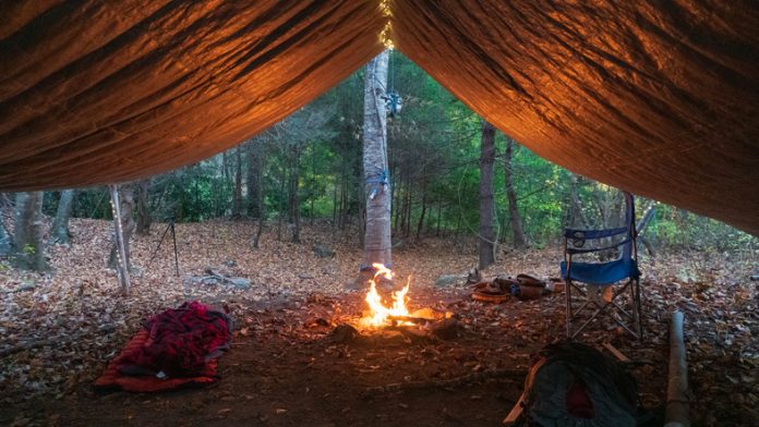 Primitive Tarp Shelter with campfire and fairy lights.