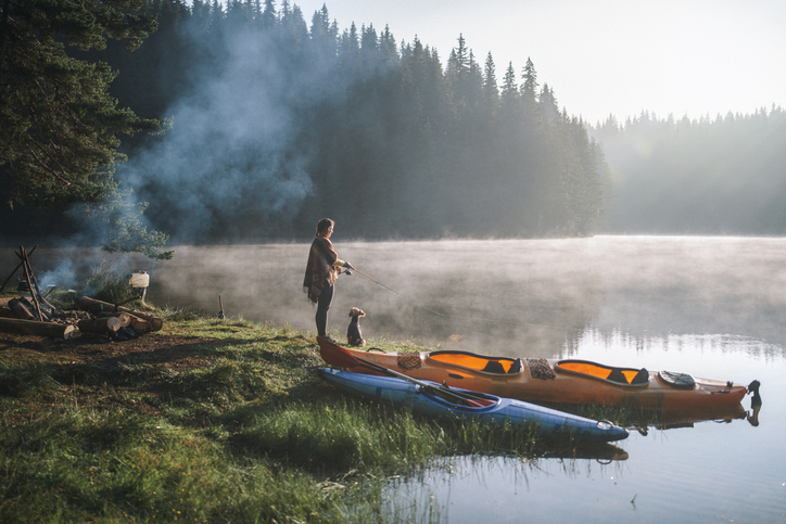 woman fishing in the morning during camping in the mountain lake.