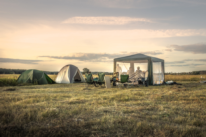 Camping site with camping tents on summer field sunset sky during camping holidays