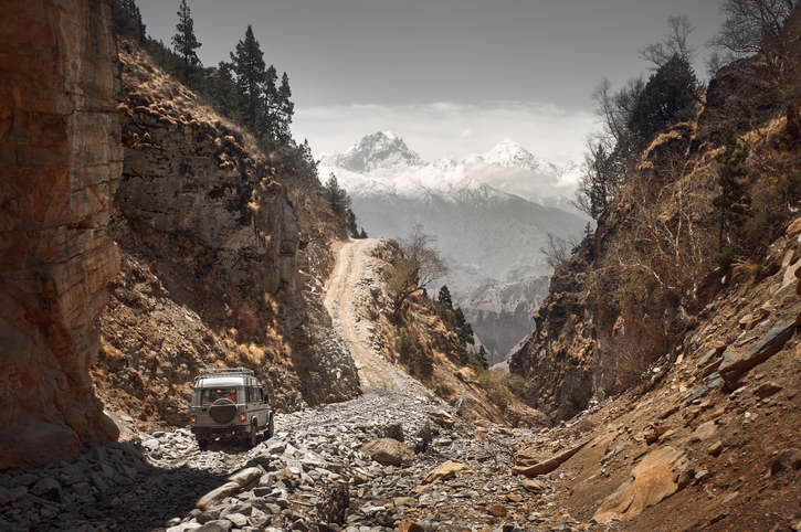 Off-road vehicle goes an extreme mountain path during an expedition to Himalayas