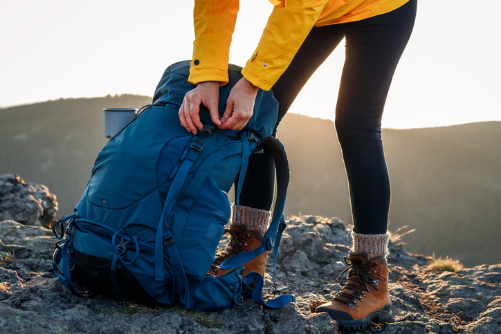 Woman opening backpack after climbing mountain peak
