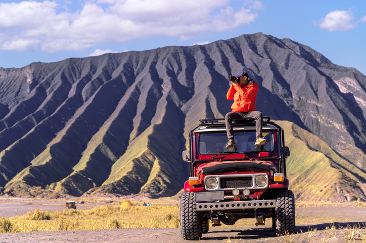  traveller take a photo on the top of advanture car in bromo volcano mountain