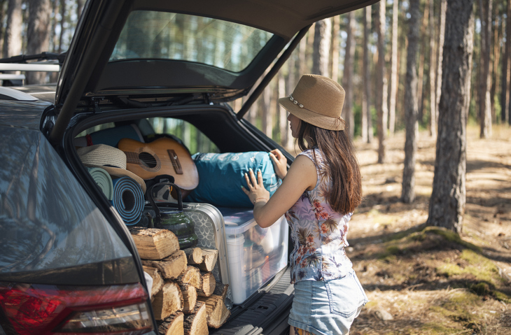Woman unloading camping equipment from a full trunk