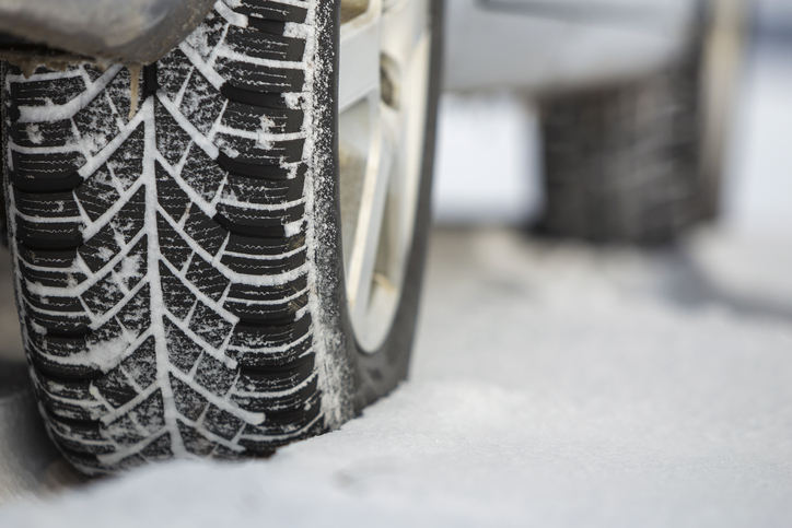 Close up of a car tire parked on snowy road on winter day. 