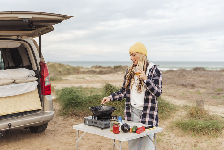 woman traveler prepares food on portable gas stove