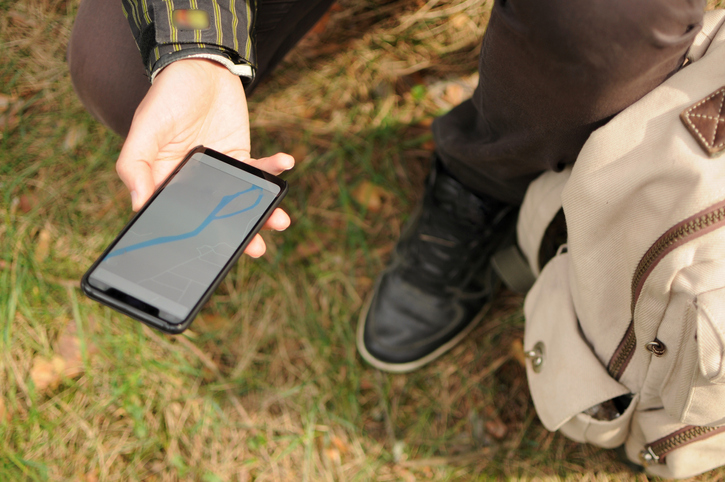 Top view of man is searching for a way using gps navigator on phone in forest