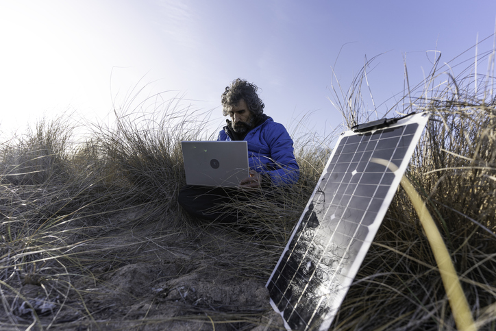 Man works on laptop powered by solar panels