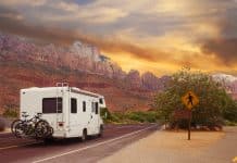 RV on the road near red rocks and as pedestrian sign