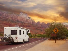 RV on the road near red rocks and as pedestrian sign