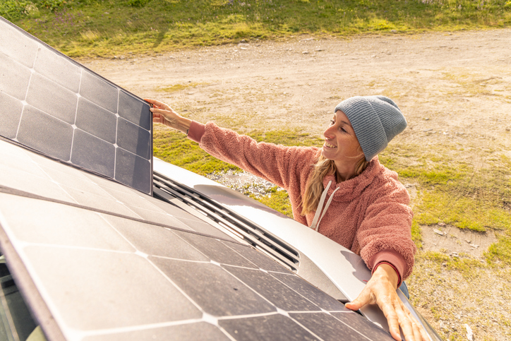 Woman camping setting up a solar panel