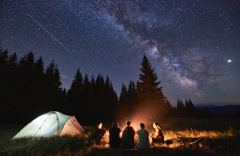 Tent camping with friends around a fire under the stars