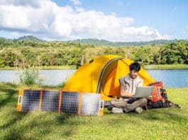 Solar Panels next to a yellow tent with a man on a lap top