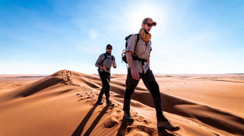 Two men walking in the dunes of the Wahiba deserts in Oman.